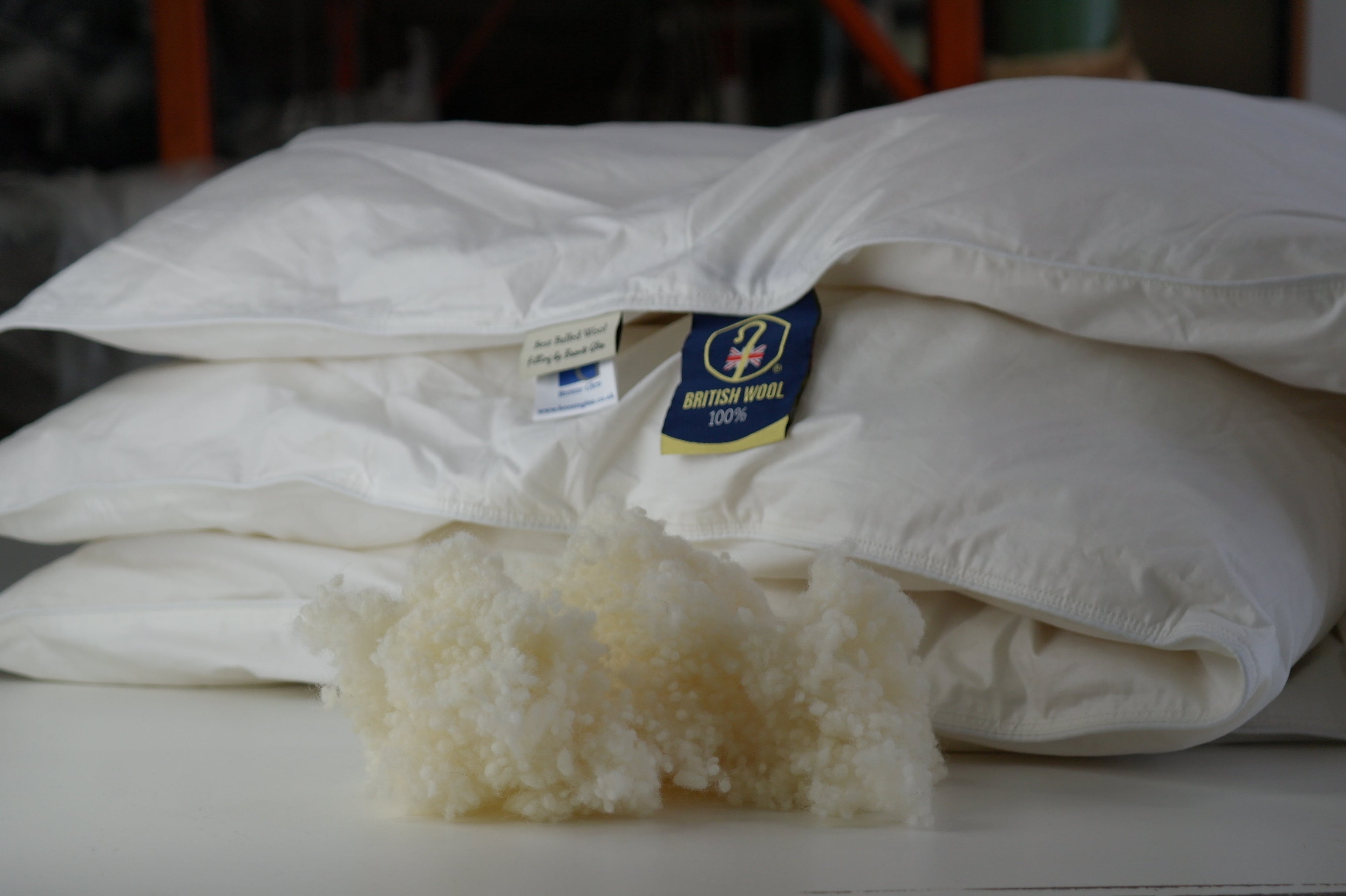 White Woolups wool duvet with visible brand labels and filling on a blurred background